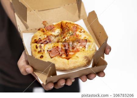 A human hand holding pizza on a cardboard box A human hand holding pizza on a cardboard box 106783206