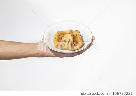 A human hand holding a side dish on a plate 106783221