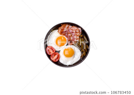 Tasty breakfast consists of eggs, bacon, beans, tomatoes, with spices and herbs Tasty breakfast consists of eggs, bacon, beans, tomatoes, with spices and herbs 106783450