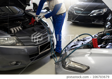 Close-up of a mechanic hand charging a car battery Car repair with jumper cables for transportation 106783679