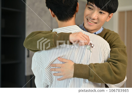 Happy gay man couple celebrating moving into new home and hugging each other. LGBTQ, relocation and real estate property Happy gay man couple celebrating moving into new home and hugging each other. LGBTQ, relocation and real estate property 106783985