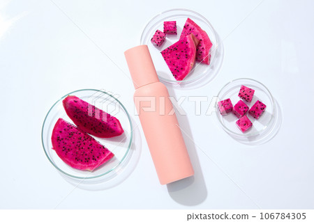 A bottle in ink color is displayed with glass petri dishes of red dragon fruit slices. Dragon fruit (Hylocereus) contains vitamin C which is a potent antioxidant A bottle in ink color is displayed with glass petri dishes of red dragon fruit slices. Dragon fruit (Hylocereus) contains vitamin C which is a potent antioxidant 106784305