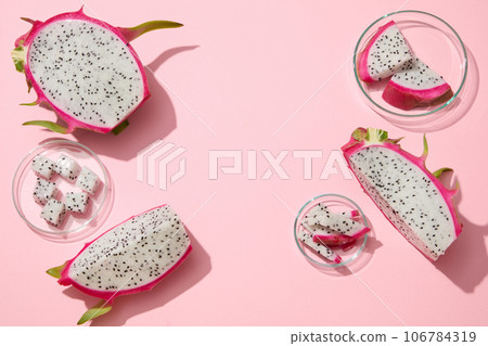 White dragon fruit cut in cubes and slices are arranged against pastel pink background. Blank space in the middle for beauty product presentation of Dragon fruit (Hylocereus) extract 106784319