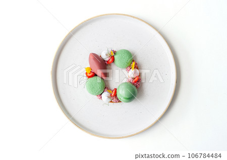 Bright dessert on a white plate with strawberries and mousse 106784484