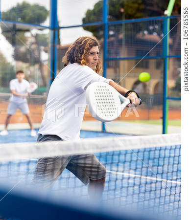 Sporty resolved man playing padel on open court 106785566