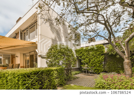 a house with trees and bushes in the front yard, as seen from the ground up close to the building a house with trees and bushes in the front yard, as seen from the ground up close to the building 106786524