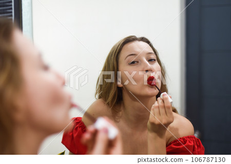 Blond beautiful woman aplying a red lipstick and looking at the mirror 106787130
