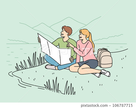 Happy couple of travelers sitting on lawn during hike in national park with lake and holding map 106787715