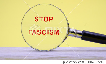 Phrase STOP FASCISM lettering on through a magnifying glass on a light background Phrase STOP FASCISM lettering on through a magnifying glass on a light background 106788596