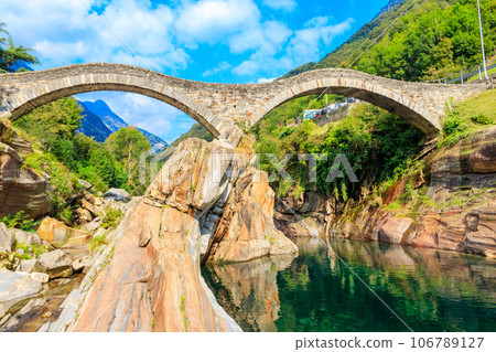 Ancient double arch stone Roman bridge (Ponte dei Salti) over the clear water of the Verzasca river in Lavertezzo ,Verzasca Valley, Ticino Canton, Switzerland Ancient double arch stone Roman bridge (Ponte dei Salti) over the clear water of the Verzasca river in Lavertezzo ,Verzasca Valley, Ticino Canton, Switzerland 106789127