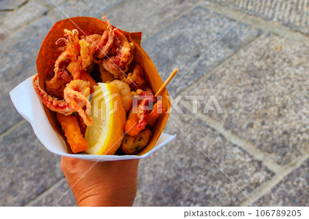 Typical Italian appetizer (Fritto misto di pesce) mix of fried seafood i female hand. Healthy snack in Genoa, Cinque Terre and Portofino Typical Italian appetizer (Fritto misto di pesce) mix of fried seafood i female hand. Healthy snack in Genoa, Cinque Terre and Portofino 106789205