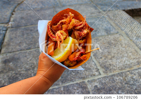Typical Italian appetizer (Fritto misto di pesce) mix of fried seafood i female hand. Healthy snack in Genoa, Cinque Terre and Portofino 106789206