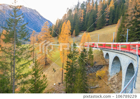 Red passenger train on Rhaetian railway in Canton Graubunden, Switzerland at autumn Red passenger train on Rhaetian railway in Canton Graubunden, Switzerland at autumn 106789229
