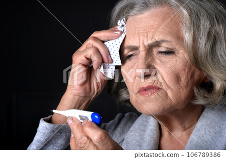 Close up portrait of sick senior woman with thermometer Close up portrait of sick senior woman with thermometer 106789386
