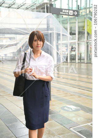 A woman walking with an umbrella in the rain A woman walking with an umbrella in the rain 106790282