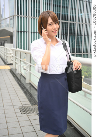 A woman calling on a smartphone on a pedestrian bridge A woman calling on a smartphone on a pedestrian bridge 106790306