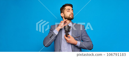 Businessman holding grapes like tie again blue studio background. Creative vision Businessman holding grapes like tie again blue studio background. Creative vision 106791183