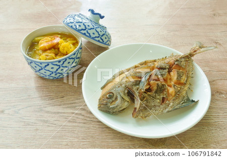 crispy fried black butterfish on plate with boiled spicy mixed vegetable shrimp curry soup in bowl crispy fried black butterfish on plate with boiled spicy mixed vegetable shrimp curry soup in bowl 106791842