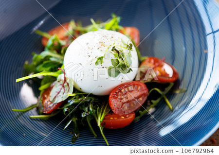 Burrata with paprika-truffle jam and cherry-cluster tomato salad. Delicious healthy Italian traditional food closeup served for lunch in modern gourmet cuisine restaurant 106792964