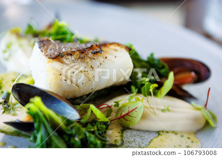 Cod fillet with cauliflower cream, asparagus, clam-wine sauce and mussles. Delicious seafood fish closeup served on a table for lunch in modern cuisine gourmet restaurant 106793008