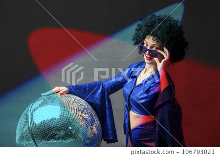 A woman with a disco ball in an afro wig in Stock Photo