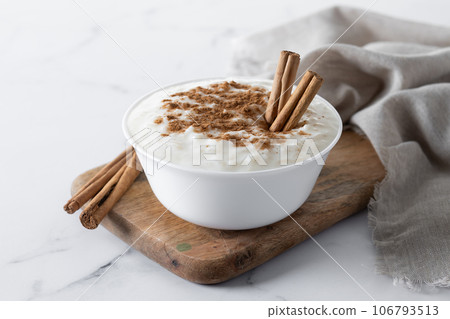 Arroz con leche. Rice pudding with cinnamon in clay bowl on white marble 106793513