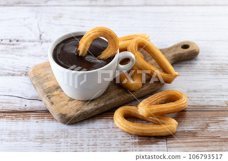 Traditional Spanish churros with hot chocolate breakfast on wooden table Traditional Spanish churros with hot chocolate breakfast on wooden table 106793517