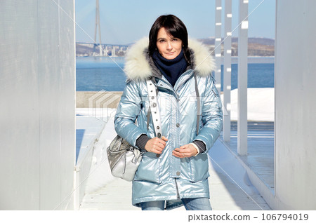 Forty five year old Russian woman smiling, looking at the camera on an early spring  day 106794019