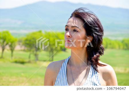 Portrait of a 45 y.o. Russian woman smiling and looking to the side against the background of a field. Portrait of a 45 y.o. Russian woman smiling and looking to the side against the background of a field. 106794047