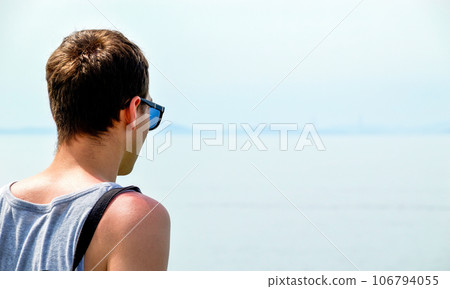 Young man in singlet and sunglasses looking at the Japanese sea. Much copy space Young man in singlet and sunglasses looking at the Japanese sea. Much copy space 106794055