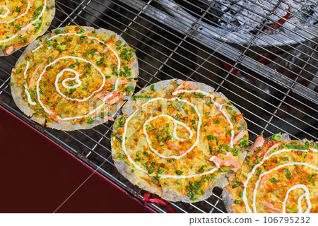 Grilled vietnamese pancake with eggs, sausages and sauces in vietnamese night market in Da Lat Grilled vietnamese pancake with eggs, sausages and sauces in vietnamese night market in Da Lat 106795232