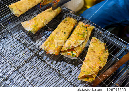 Grilled vietnamese pancake with eggs, sausages and sauces in vietnamese night market in Da Lat Grilled vietnamese pancake with eggs, sausages and sauces in vietnamese night market in Da Lat 106795233