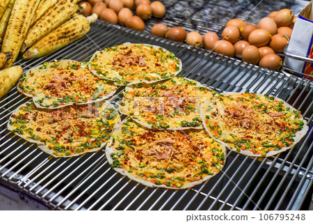 Grilled vietnamese pancake with eggs, sausages and sauces in vietnamese night market in Da Lat Grilled vietnamese pancake with eggs, sausages and sauces in vietnamese night market in Da Lat 106795248