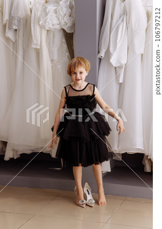 Little girl in a black evening dress in a clothing boutique Little girl in a black evening dress in a clothing boutique 106797212