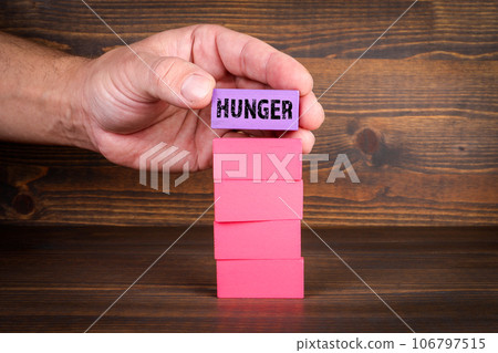 HUNGER. Colorful blocks in a pile on a wooden texture background 106797515