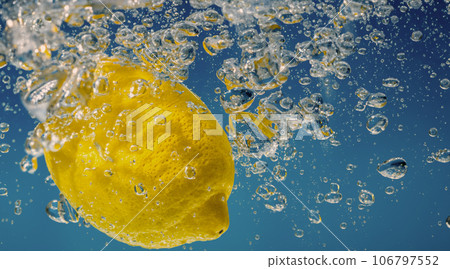 Underwater lemon slice in soda water or lemonade with bubbles. Refreshing soda tonic fizzy cocktail. Close up of lemons and ice cubes in glass. Lime in splashing sparkling water cold drink beverage. 106797552