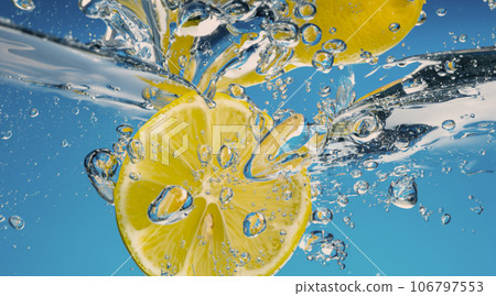 Underwater lemon slice in soda water or lemonade with bubbles. Refreshing soda tonic fizzy cocktail. Close up of lemons and ice cubes in glass. Lime in splashing sparkling water cold drink beverage. 106797553