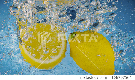 Underwater lemon slice in soda water or lemonade with bubbles. Refreshing soda tonic fizzy cocktail. Close up of lemons and ice cubes in glass. Lime in splashing sparkling water cold drink beverage. Underwater lemon slice in soda water or lemonade with bubbles. Refreshing soda tonic fizzy cocktail. Close up of lemons and ice cubes in glass. Lime in splashing sparkling water cold drink beverage. 106797564