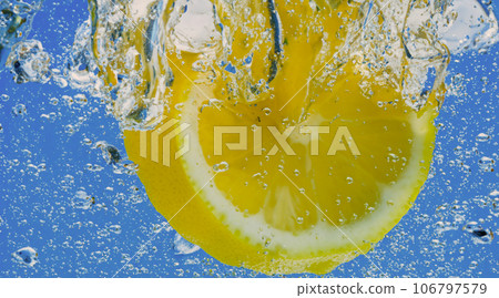 Underwater lemon slice in soda water or lemonade with bubbles. Refreshing soda tonic fizzy cocktail. Close up of lemons and ice cubes in glass. Lime in splashing sparkling water cold drink beverage. Underwater lemon slice in soda water or lemonade with bubbles. Refreshing soda tonic fizzy cocktail. Close up of lemons and ice cubes in glass. Lime in splashing sparkling water cold drink beverage. 106797579