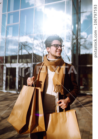 Stylish man with paper packages after shopping. Sale, consumerist, lifestyle concept. 106797593