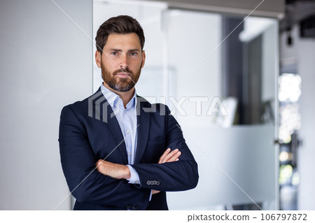 Portrait of mature experienced financier businessman, man thinking seriously looking at camera with crossed arms, confident investor banker inside office workplace in business suit. 106797872