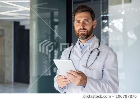 Portrait of senior mature experienced doctor, man in medical coat inside clinic looking at camera, senior doctor holding tablet computer, for online remote consultation of patients. Portrait of senior mature experienced doctor, man in medical coat inside clinic looking at camera, senior doctor holding tablet computer, for online remote consultation of patients. 106797876