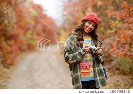 Young woman- tourist taking pictures in autumn forest. Rest, relaxation, tourism, lifestyle concept. 106798306