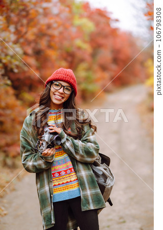 Young woman- tourist taking pictures in autumn forest. Rest, relaxation, tourism, lifestyle concept. Young woman- tourist taking pictures in autumn forest. Rest, relaxation, tourism, lifestyle concept. 106798308