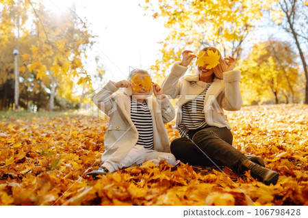 Mother and daughter walking in park and enjoying beautiful autumn nature. Childhood, walk, family. Mother and daughter walking in park and enjoying beautiful autumn nature. Childhood, walk, family. 106798428