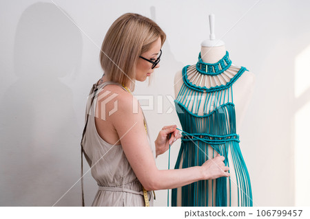 Craftswoman braids green threads making elegant macrame dress in fashion atelier young woman creates glamorous clothes in craft sewing workshop outfit model 106799457