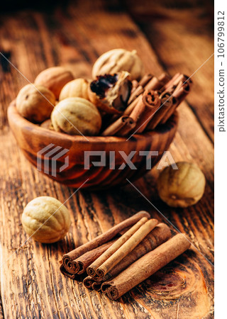 Cinnamon sticks and dried limes in wooden bowl 106799812