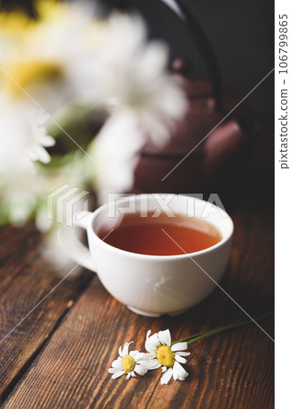 Cup of black tea and two chamomile flowers 106799865
