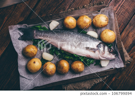 Fresh Sea Bass Stuffed with Sorrel Ready to Be Cooked with New Potatoes and Onion 106799894