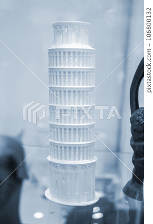 Art object printed on 3D printer. Figure Leaning Tower of Pisa prototype of white color. Model printed on 3D printer from melted plastic close-up. Concept new modern innovation printing technology Art object printed on 3D printer. Figure Leaning Tower of Pisa prototype of white color. Model printed on 3D printer from melted plastic close-up. Concept new modern innovation printing technology 106800132